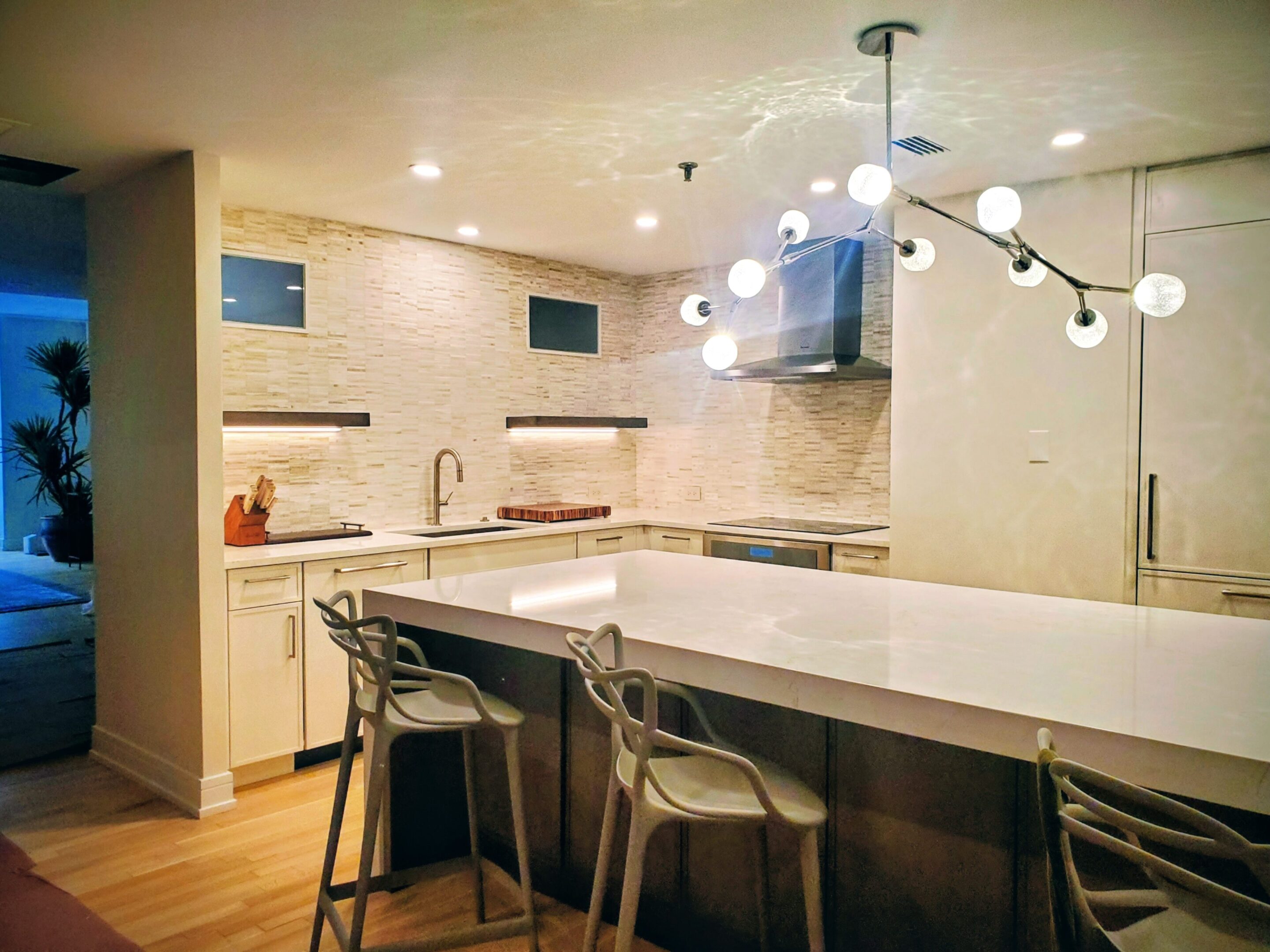Modern kitchen with white countertops and stylish lighting.
