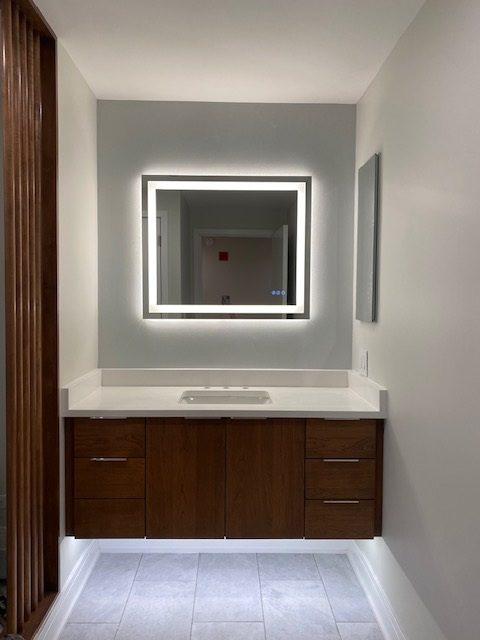Modern bathroom vanity with illuminated mirror and wooden cabinets.